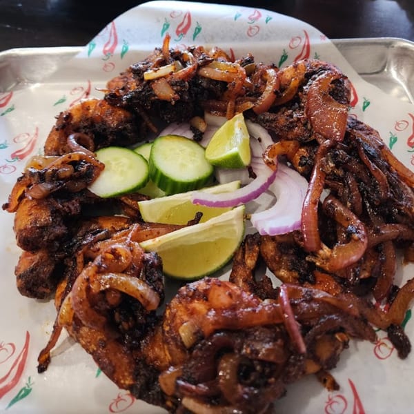 Casa Agave's fried fish with caramelized onions, cucumber slices, lime wedges, and red onion.