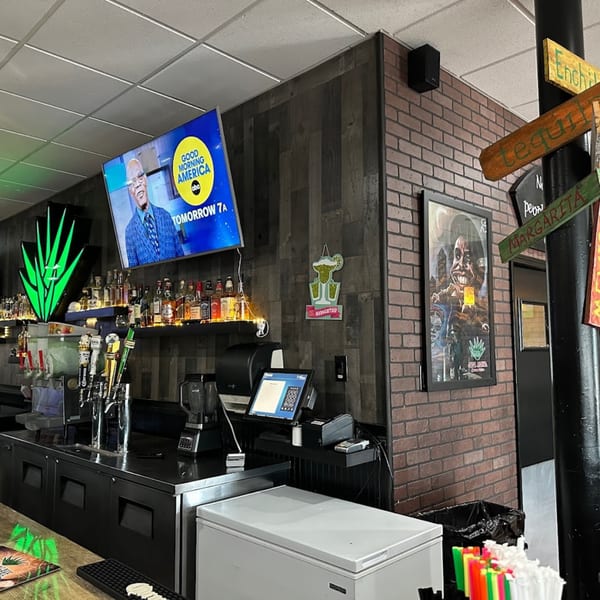 A bar area at Casa Agave with a TV showing Good Morning America, liquor bottles, and beer taps.